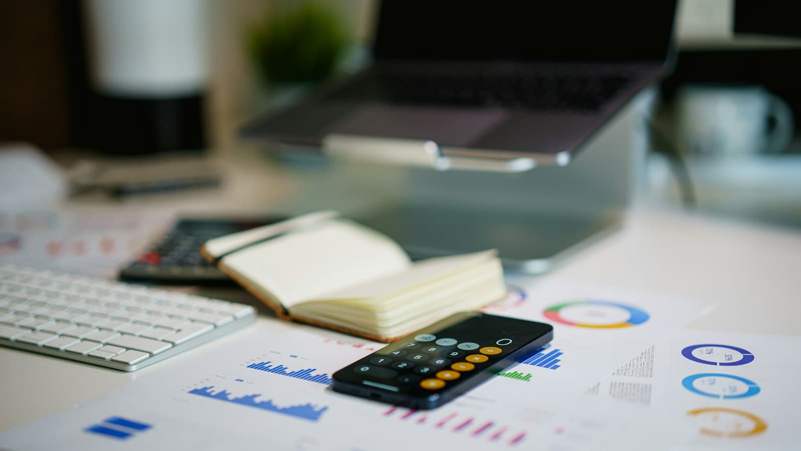 An office desk with a smartphone and financial charts.