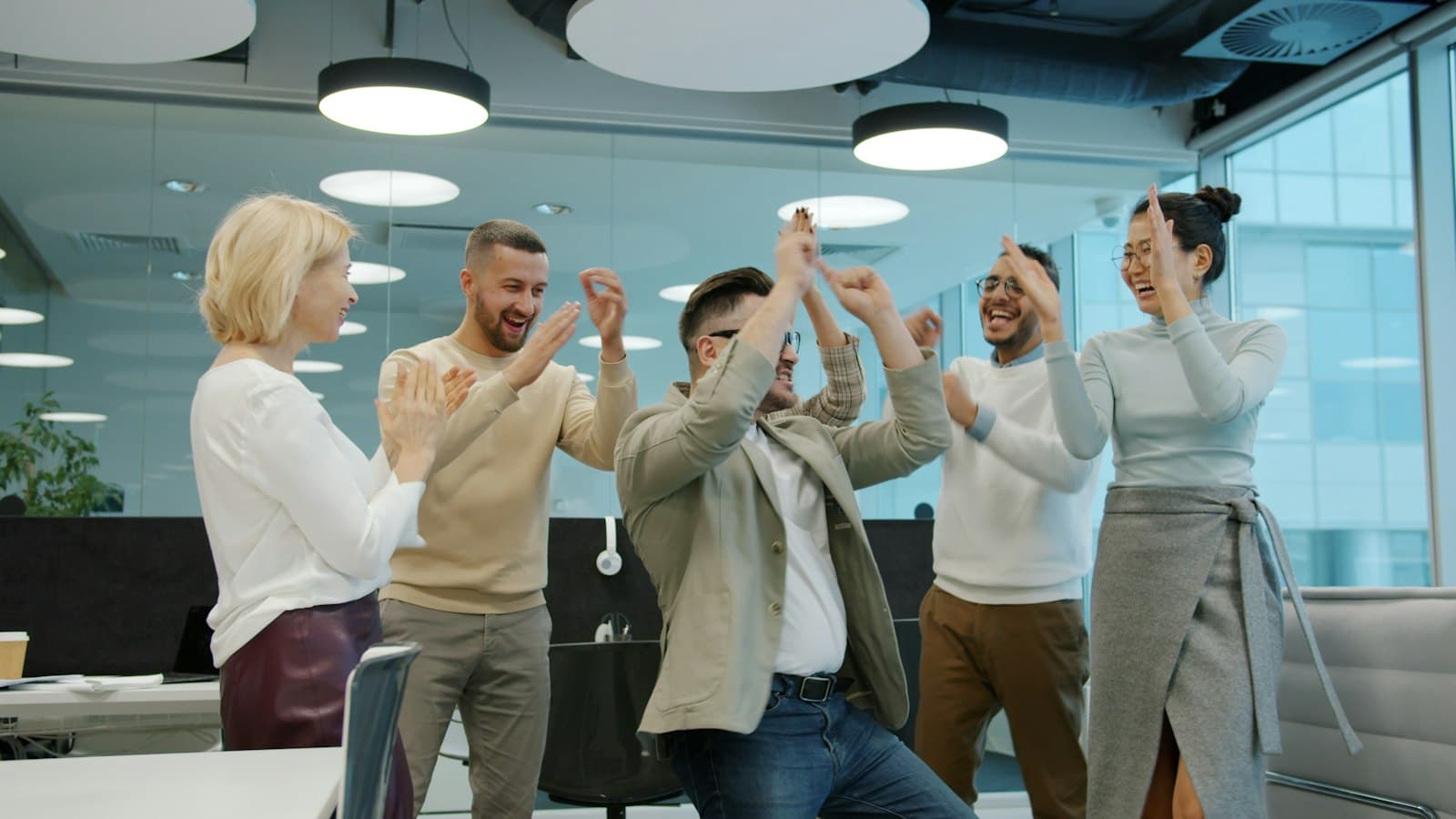 A diverse group of colleagues celebrating success in an office.