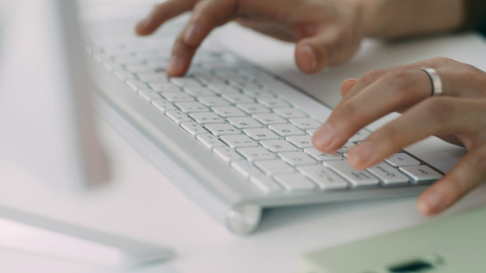 A person typing on a white laptop computer.