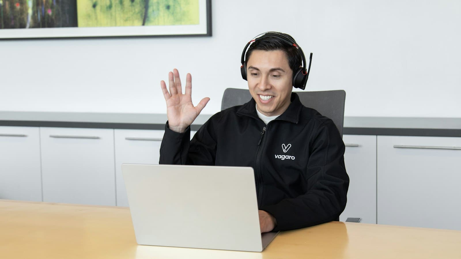 A support representative wearing headphones working at a laptop.